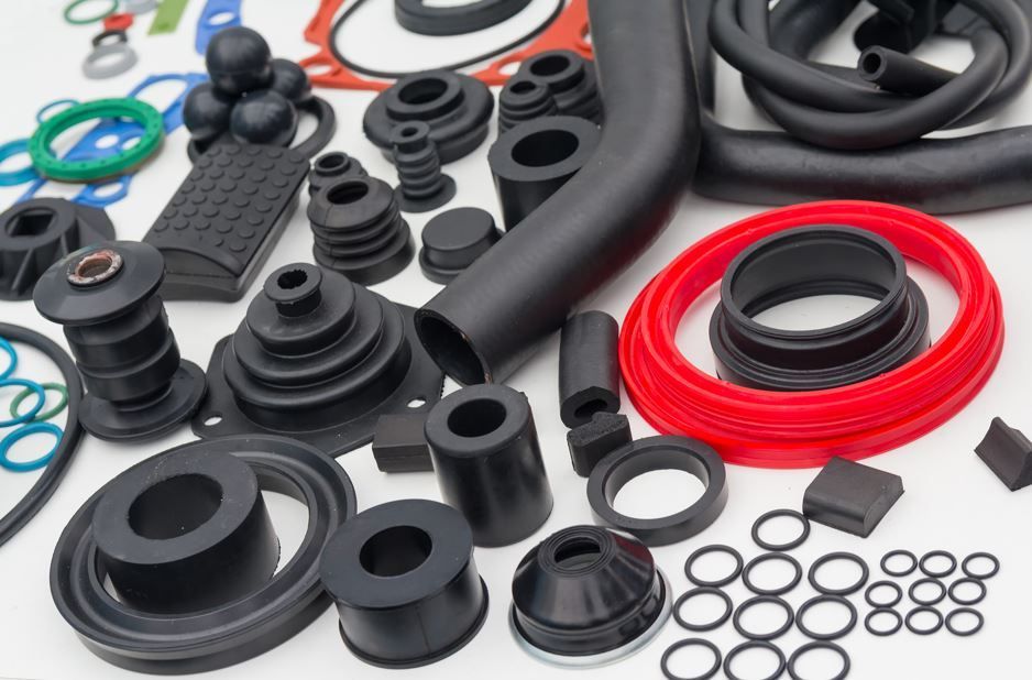Sellos, juntas y tubos de goma surtidos de color negro y rojo sobre una superficie blanca.