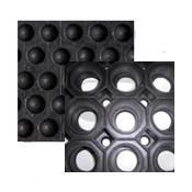 Dos alfombrillas de goma negras: una con puntos en relieve y la otra con agujeros circulares abiertos.