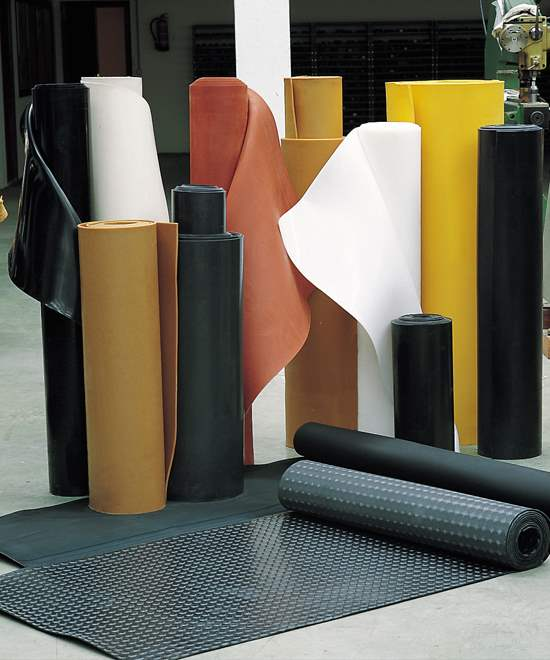 Rollos de láminas y esterillas de caucho de diversos colores, posiblemente para uso industrial, en interiores.