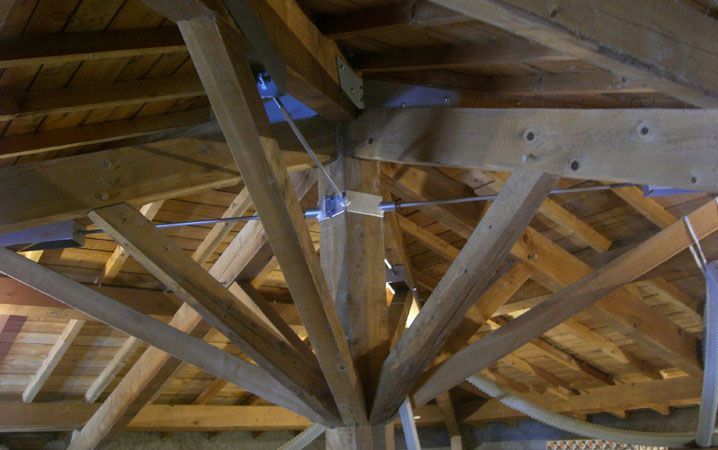Fermes de charpente en bois avec une poutre de soutien centrale sous un plafond cathédrale