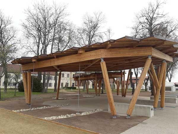 Pavillon en bois avec des supports angulaires dans un parc par temps couvert