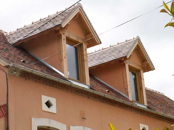 Maison orange avec deux lucarnes et un toit en tuiles rouges