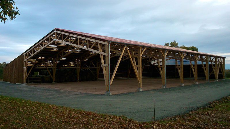 Pavillon en bois ouvert sur les côtés, avec un toit à fermes à deux versants, sur une zone pavée sous un ciel couvert