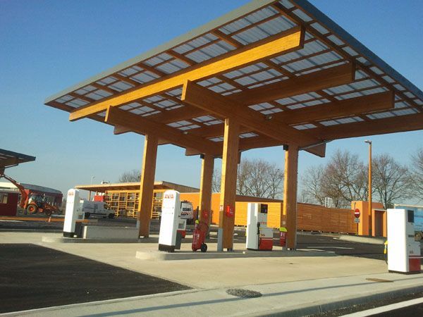 Station-service avec une auvent orange et plusieurs pompes à carburant par une journée ensoleillée