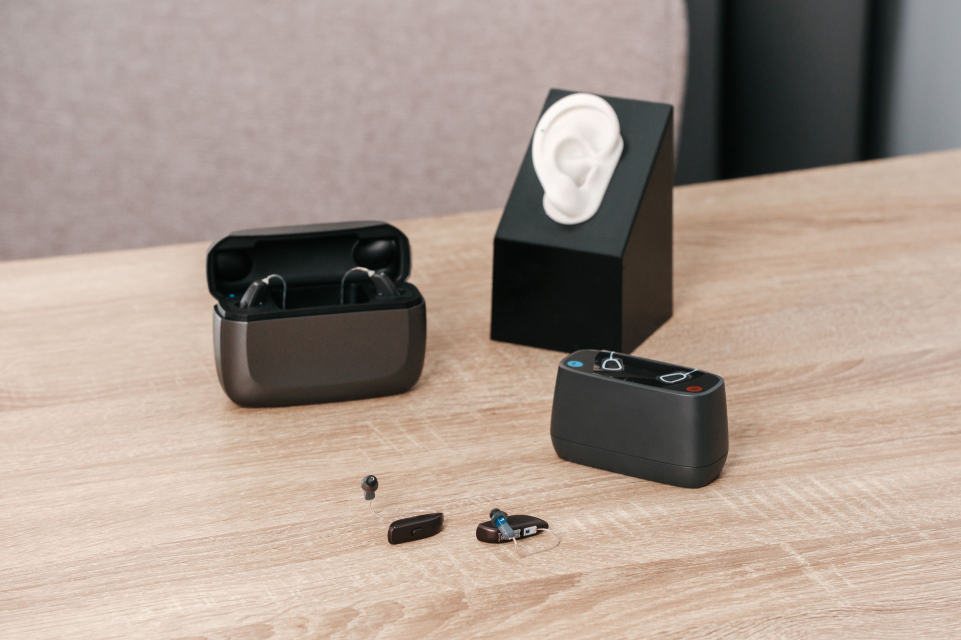 Appareils auditifs, étui de chargement et modèle d'oreille sur une table en bois.