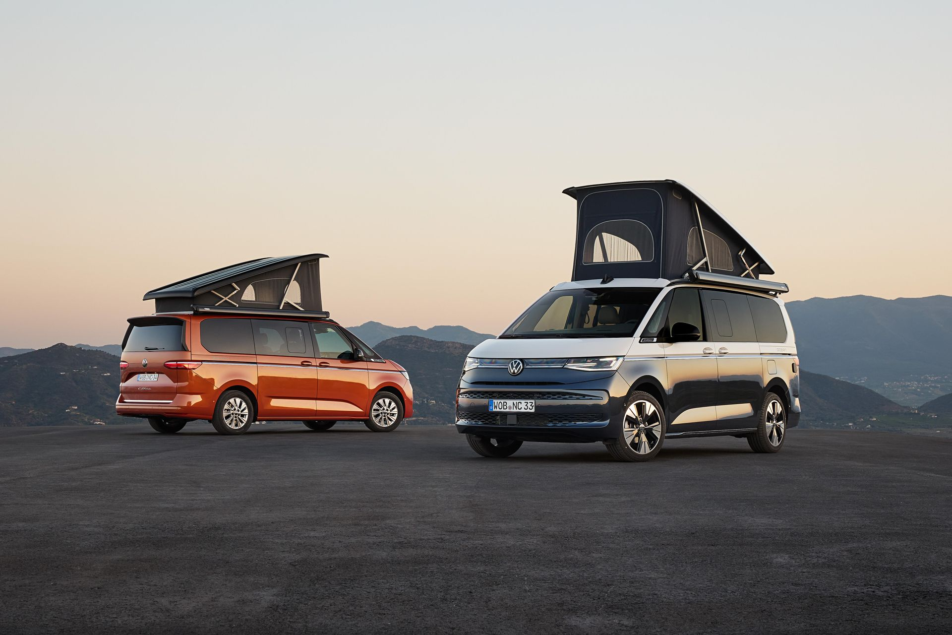 Zwei Campervans mit Dachzelten, die bei Sonnenuntergang auf einem Berg-Aussichtspunkt geparkt sind