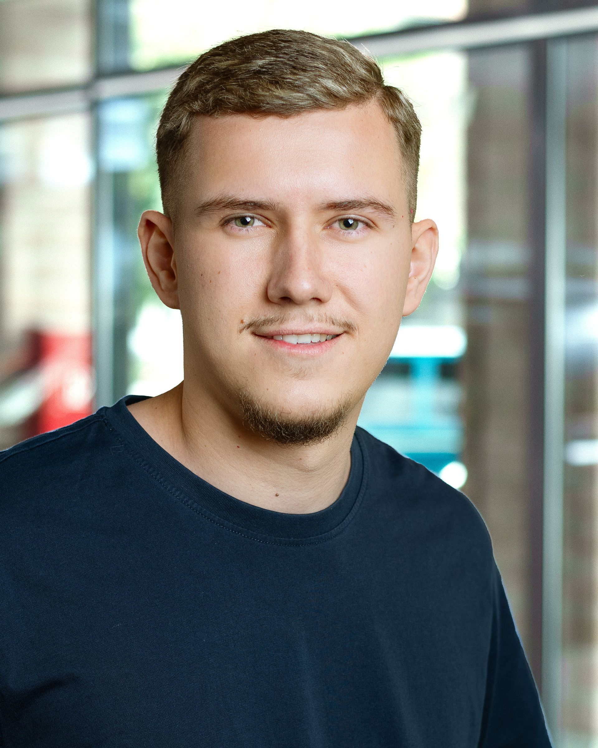 Eine Frau in einem blauen Hemd und Ohrringen lächelt in die Kamera.