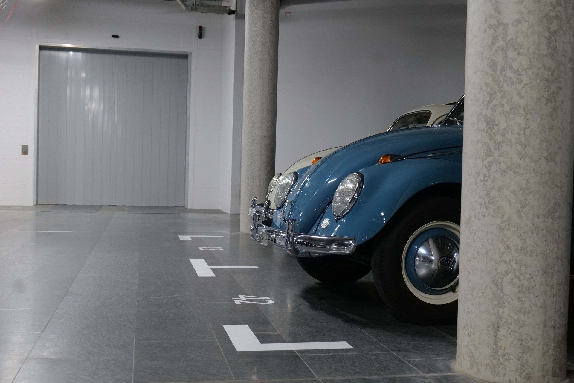 Zwei blaue Autos stehen nebeneinander in einem Parkhaus.