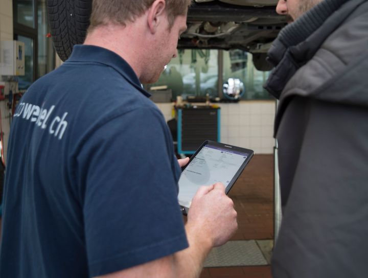 Ein Mann trägt ein T-Shirt mit der Aufschrift „Sweel Ch“ und schaut auf ein Tablet