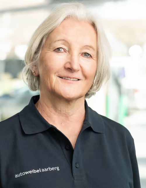 Eine Frau in einem schwarzen Poloshirt lächelt in die Kamera.