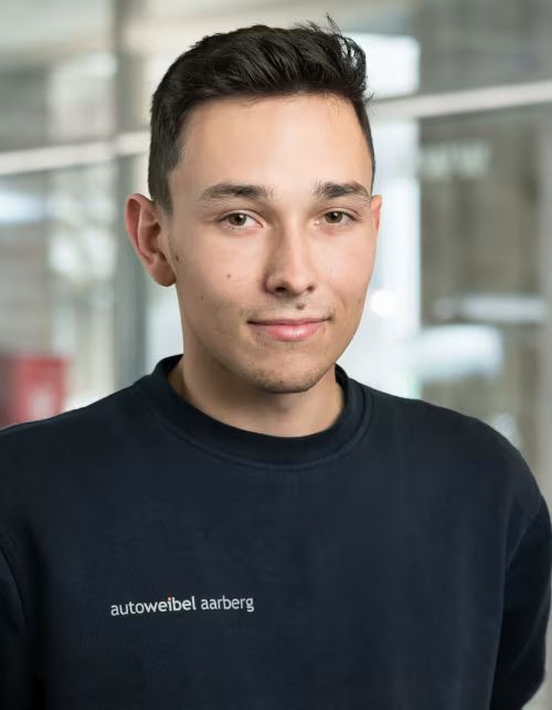 Ein junger Mann trägt ein blaues Sweatshirt mit dem Wort „Auto“ darauf.