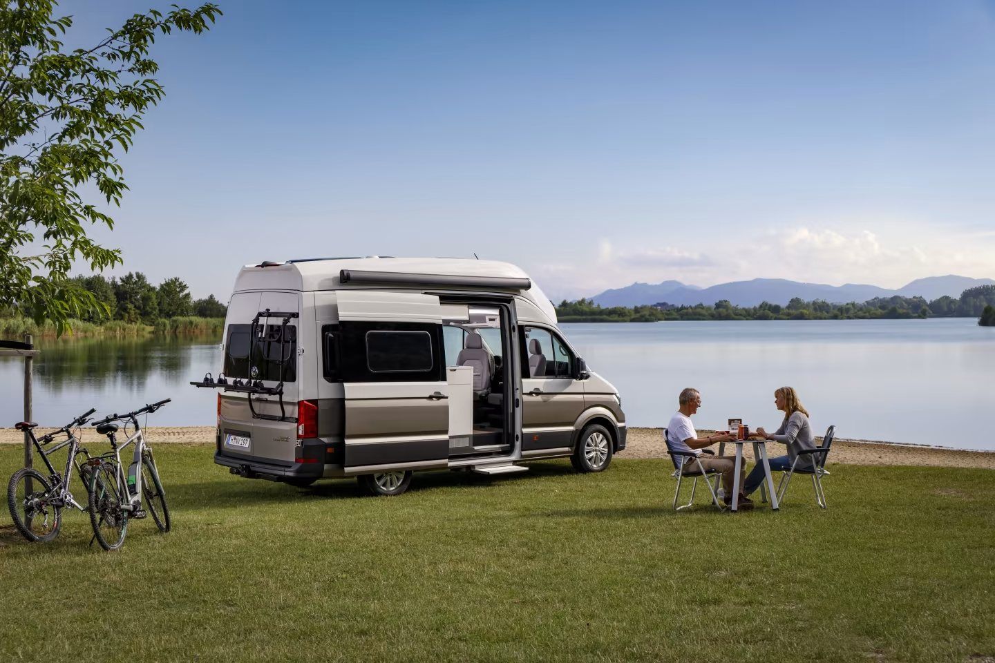 Ein Paar sitzt an einem Tisch vor einem Wohnmobil.