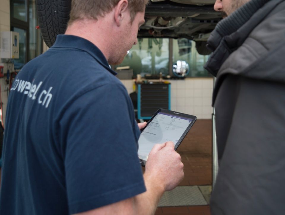 Ein Mechaniker hält ein Tablet. Foto von der Autoweibel AG