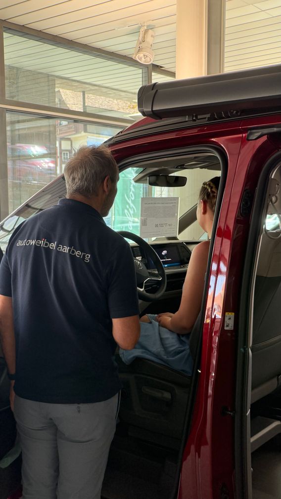 Ein Mann steht neben einer Frau in einem roten Lieferwagen.