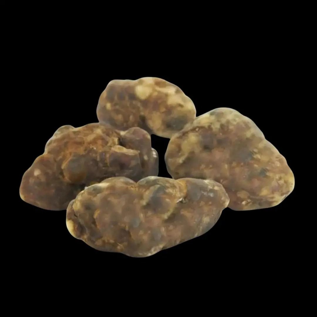 Pila de trufas pálidas y texturizadas sobre un fondo negro.