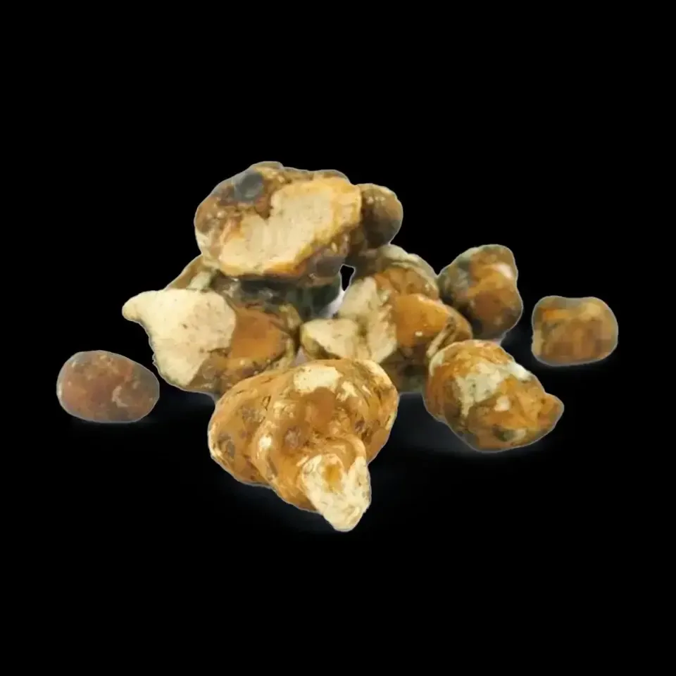 Pila de trufas blancas con exteriores moteados de color beige sobre un fondo negro.