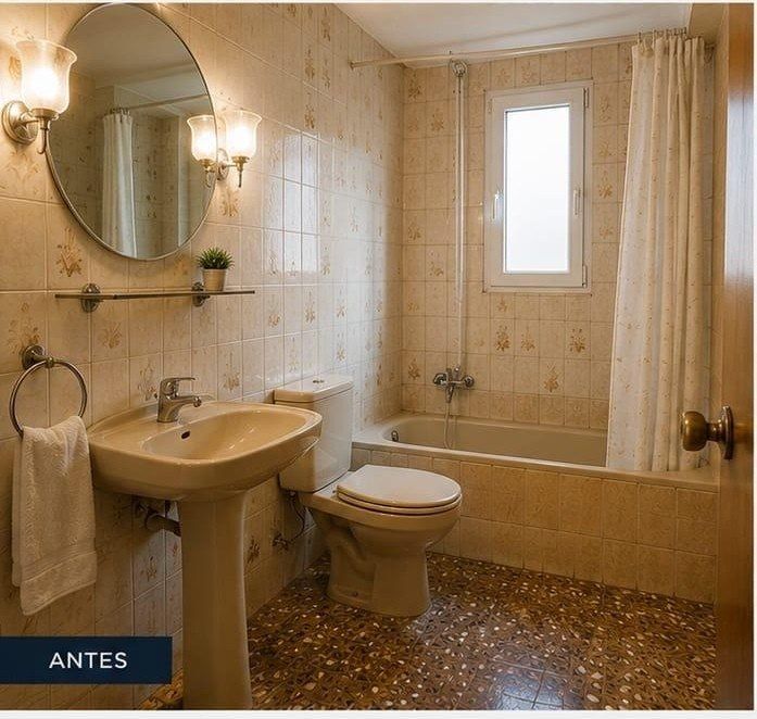 Baño con azulejos beige, lavabo, inodoro, bañera y espejo redondo; etiqueta «ANTES» en una esquina