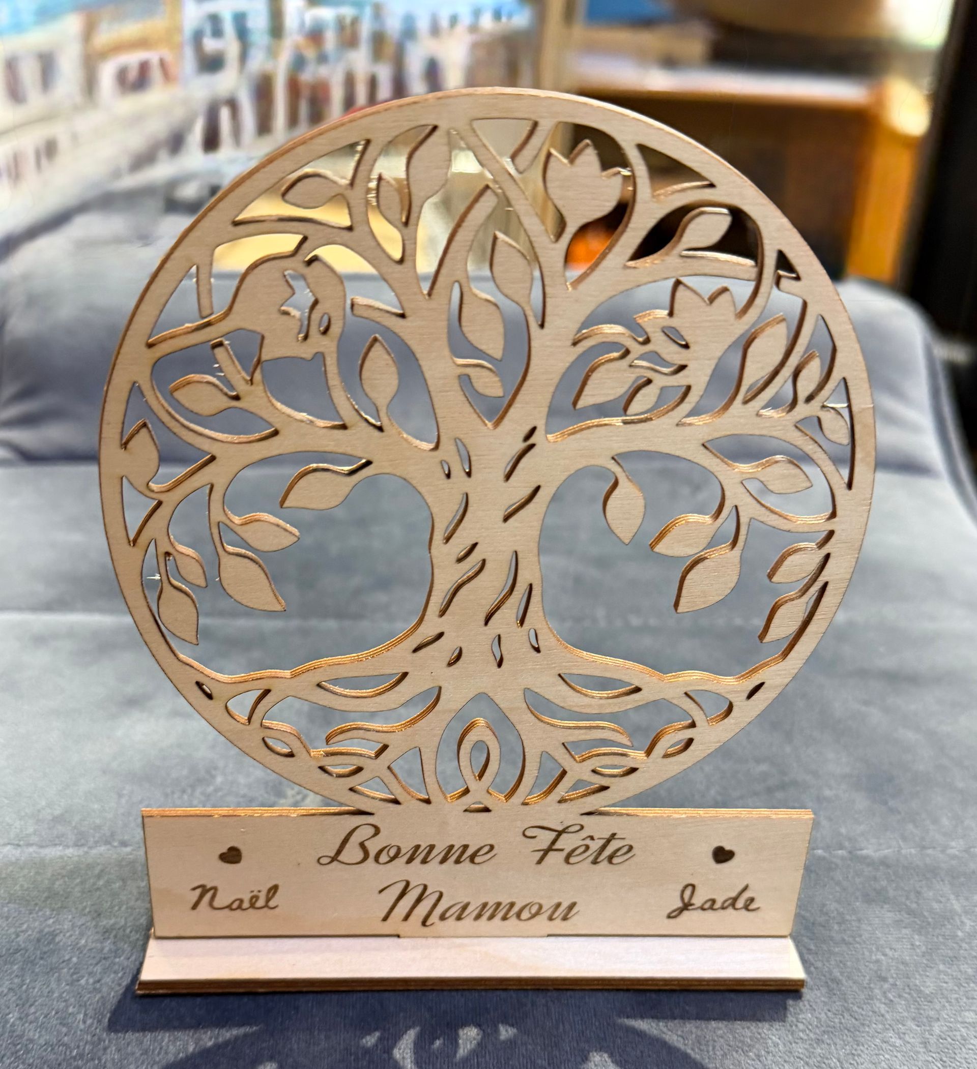 Plaque dorée représentant un arbre de vie, sur un socle en bois gravé Bonne Fête Maman, avec les noms en dessous.
