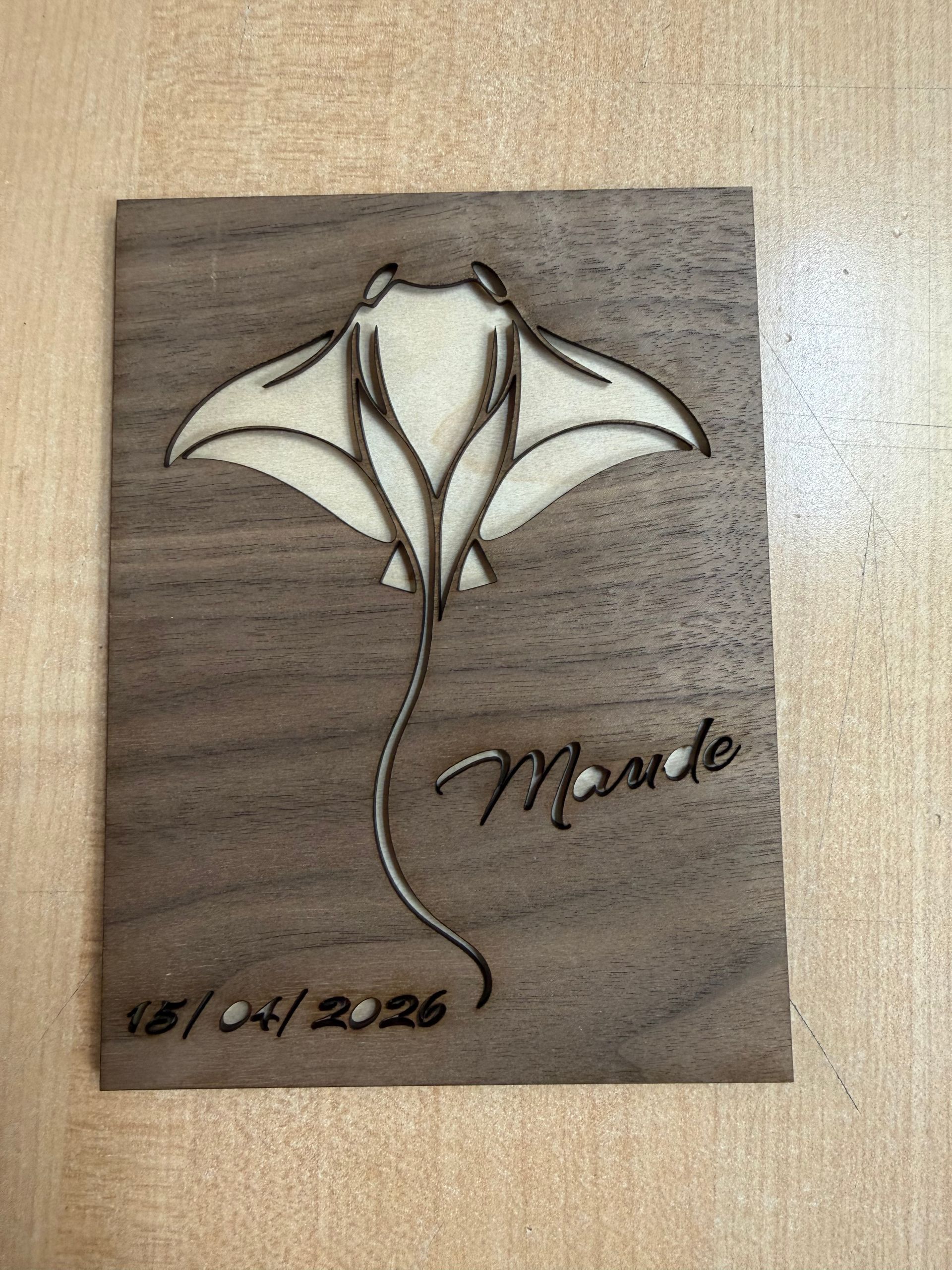Plaque en bois ornée d'une fleur stylisée et d'un prénom, datée du 16/04/2026.