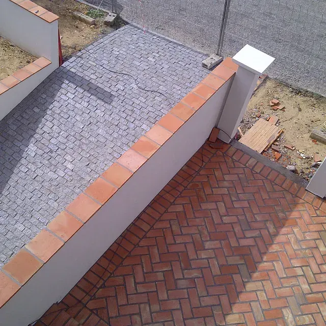 Una pasarela de ladrillo con diseño de espiga y una pared blanca