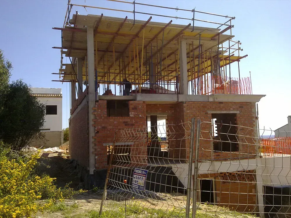 Un edificio de ladrillos en construcción con una valla alrededor.