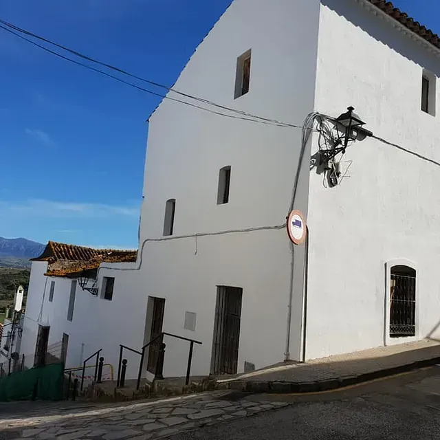 Un edificio blanco con un cartel de no estacionar al costado.