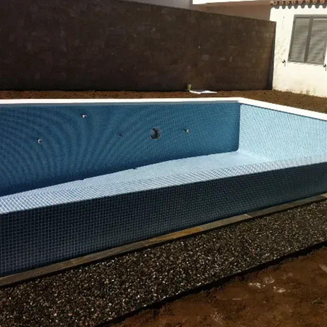 Se está construyendo una gran piscina azul en un patio trasero.