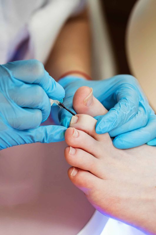Una persona se está pintando las uñas de los pies con un artista de uñas.