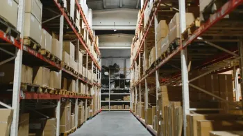 Pasillo de almacén con estantes altos apilados con cajas de cartón.
