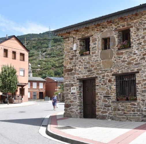Una mujer camina por una calle frente a un edificio de piedra.