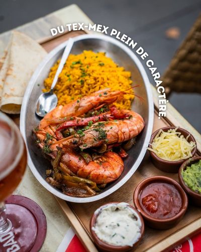 Plateau de crevettes tex-mex accompagné de riz, de sauces et de tortillas, servi sur une planche en bois
