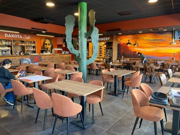 Salle de restaurant sur le thème de l’Ouest américain, avec une décoration de cactus, des tables et des chaises baignées d’une lumière chaleureuse