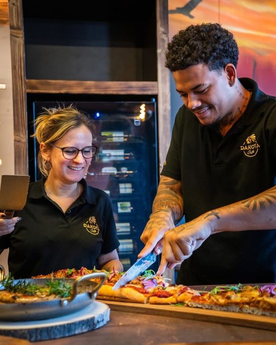 Deux membres du personnel sourient en préparant un repas ensemble dans la cuisine d’un restaurant