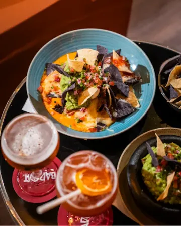Diverses boissons et un bol bleu de nachos sur une table de restaurant