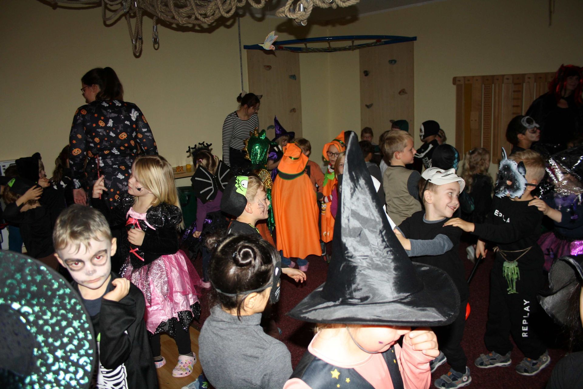 A group of children dressed in halloween costumes are dancing in a room.