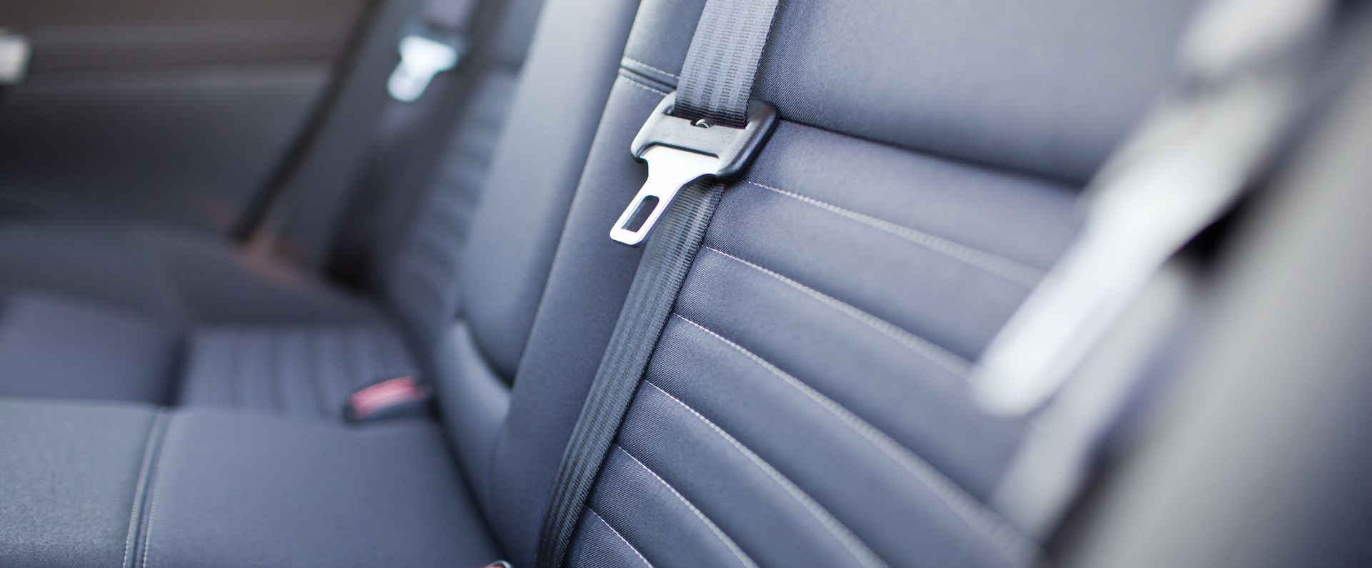 Gros plan sur la banquette arrière en cuir noir d'une voiture, l'accent étant mis sur la boucle de la ceinture de sécurité.