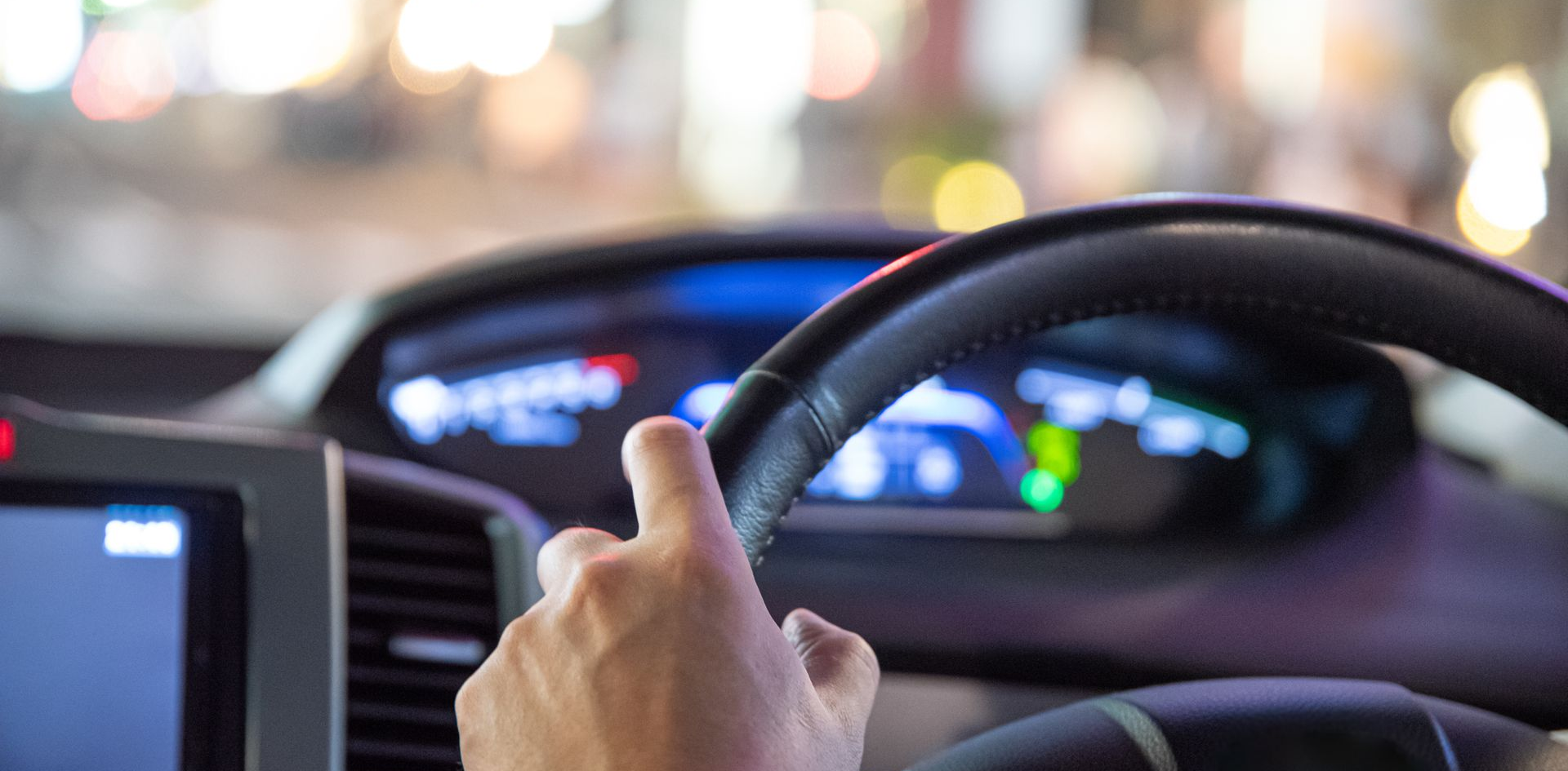 Une main sur le volant d'une voiture, conduisant de nuit.