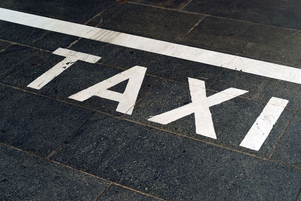 L'inscription TAXI est peinte en blanc sur de l'asphalte foncé, à côté d'une ligne blanche.