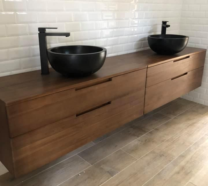 Meuble sous lavabo suspendu en bois avec deux vasques noires et robinetterie noire mate.