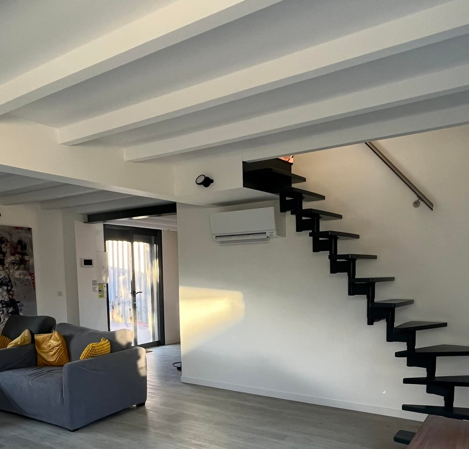 Chambre avec papier peint géométrique, climatisation, éclairage décoratif et petit lit avec une lampe rose.