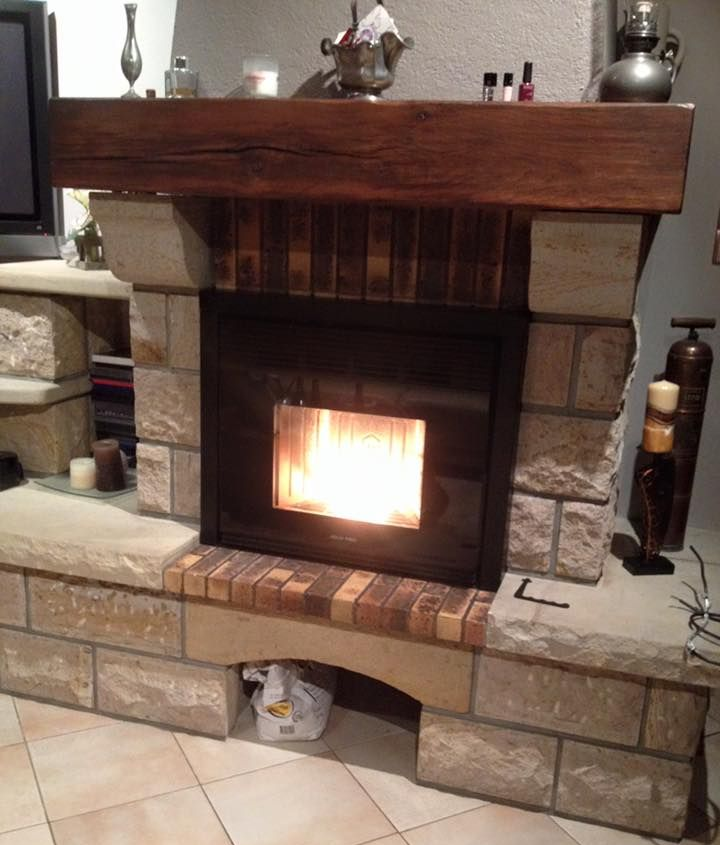 Cheminée en pierre avec un feu qui brûle, manteau en bois et foyer en pierre.