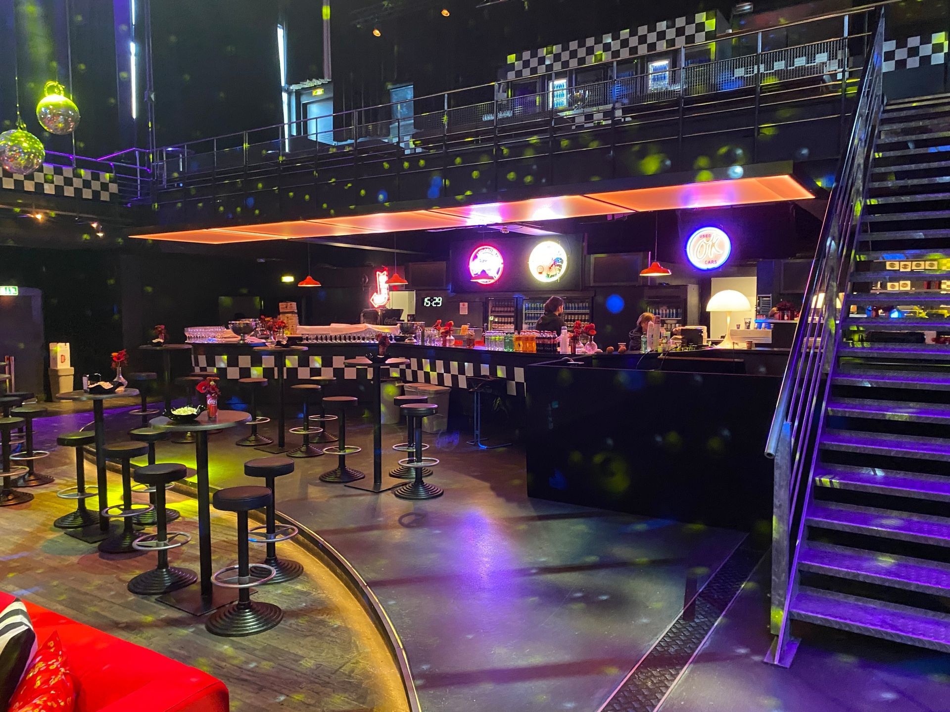 Bar décoré en damier noir et blanc, avec des tables hautes et des spots allumés