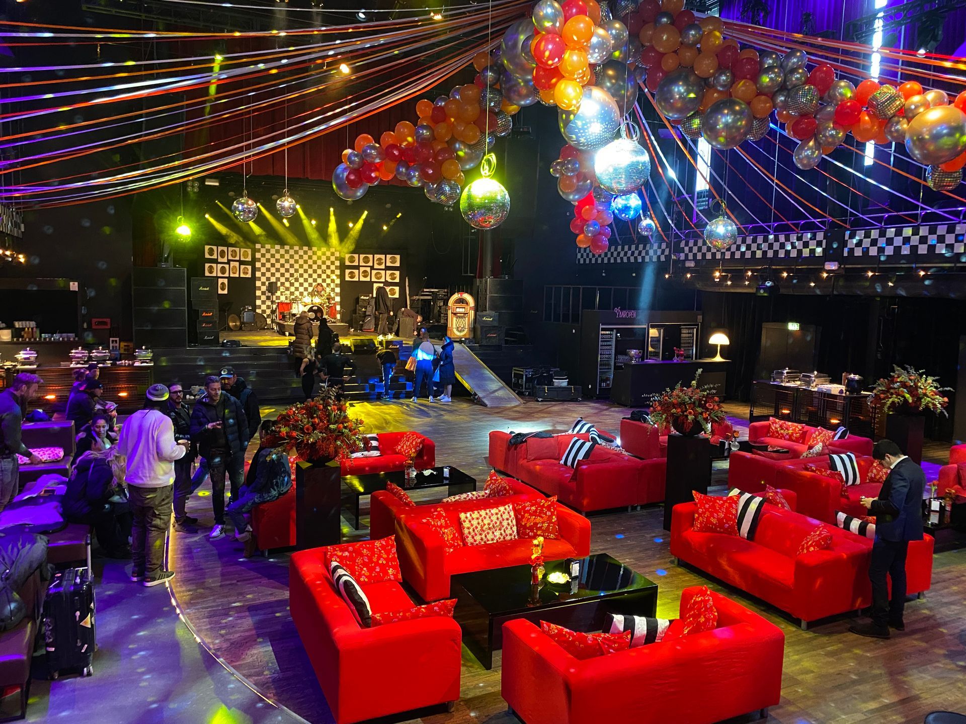 Salle avec des fauteuils et des canapés rouges décorée de ballons au plafond