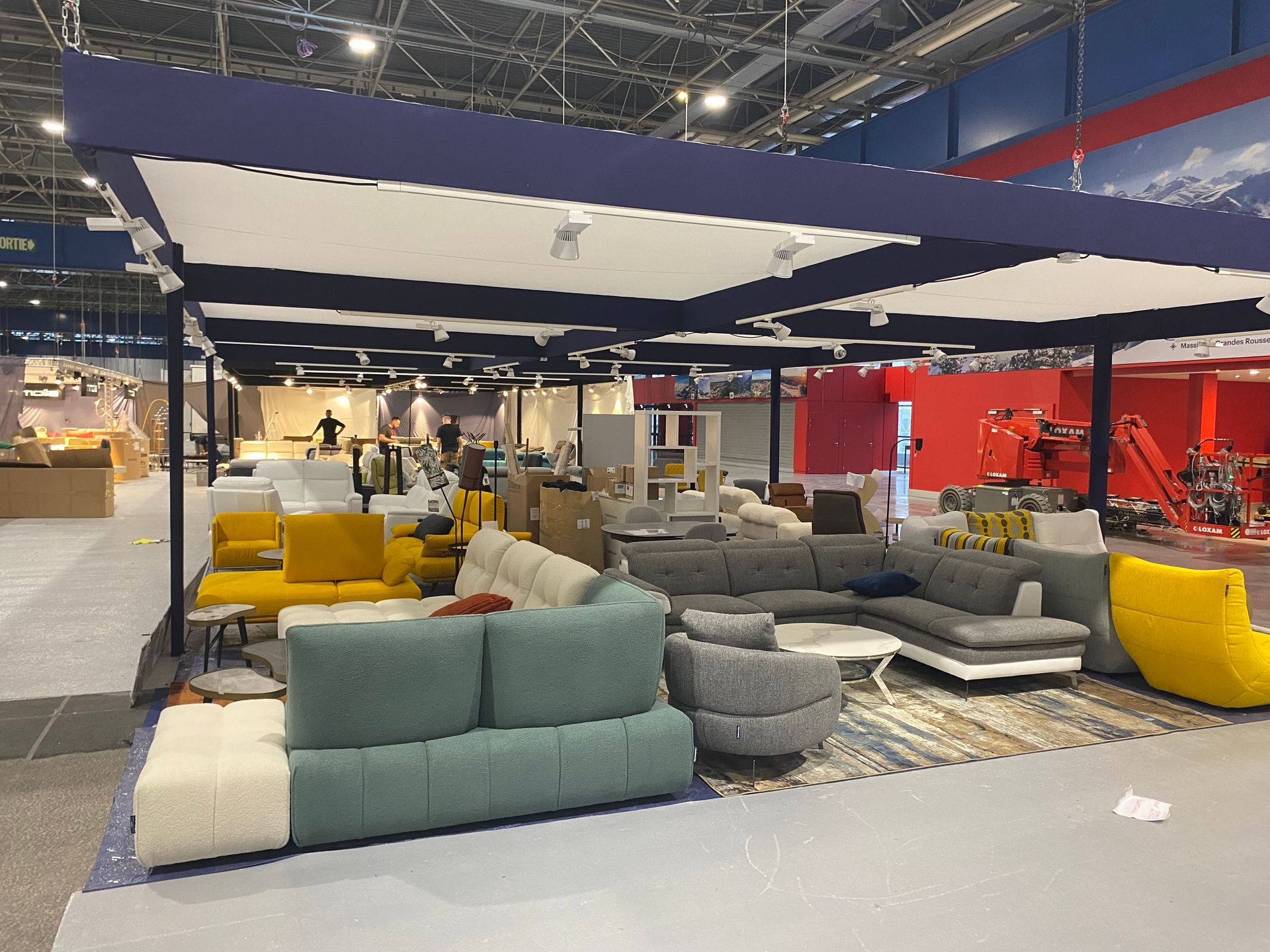 Parc des expositions avec un stand où sont installés des canapés de différentes couleurs
