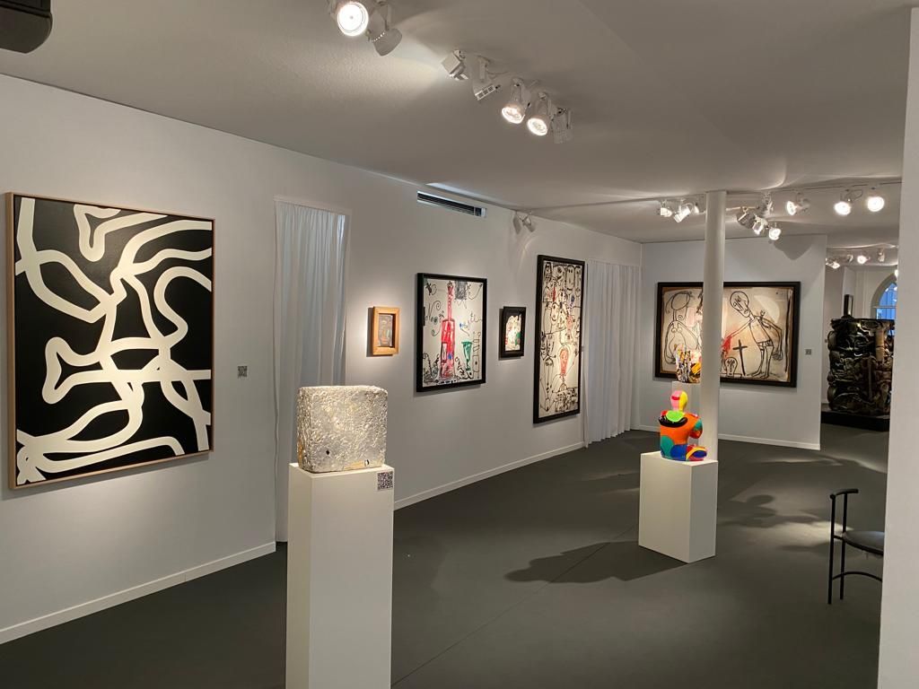 Sculptures sur des supports et des tableaux accrochés au mur dans une galerie d'art