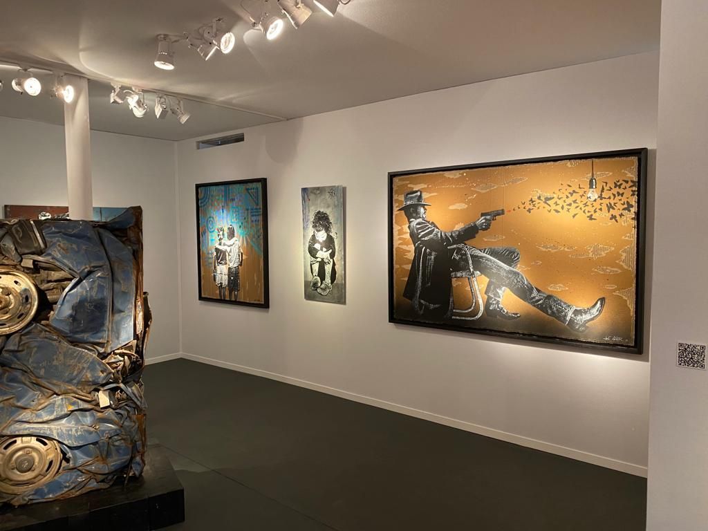 Trois tableaux sur un mur blanc dans une galerie d'art