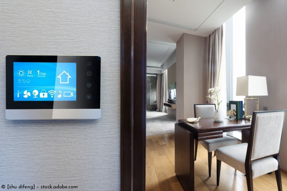 Ein an der Wand neben einer Tür angebrachtes Smart-Home-Bedienfeld gibt den Blick in einen hellen Essbereich frei.
