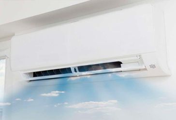 Un acondicionador de aire blanco está colgado en una pared blanca al lado de una ventana.