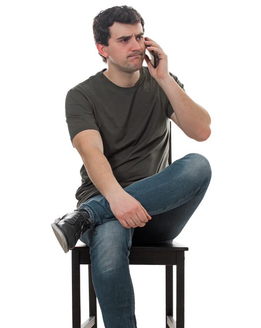 Un homme assis sur une chaise tient son téléphone à l'oreille