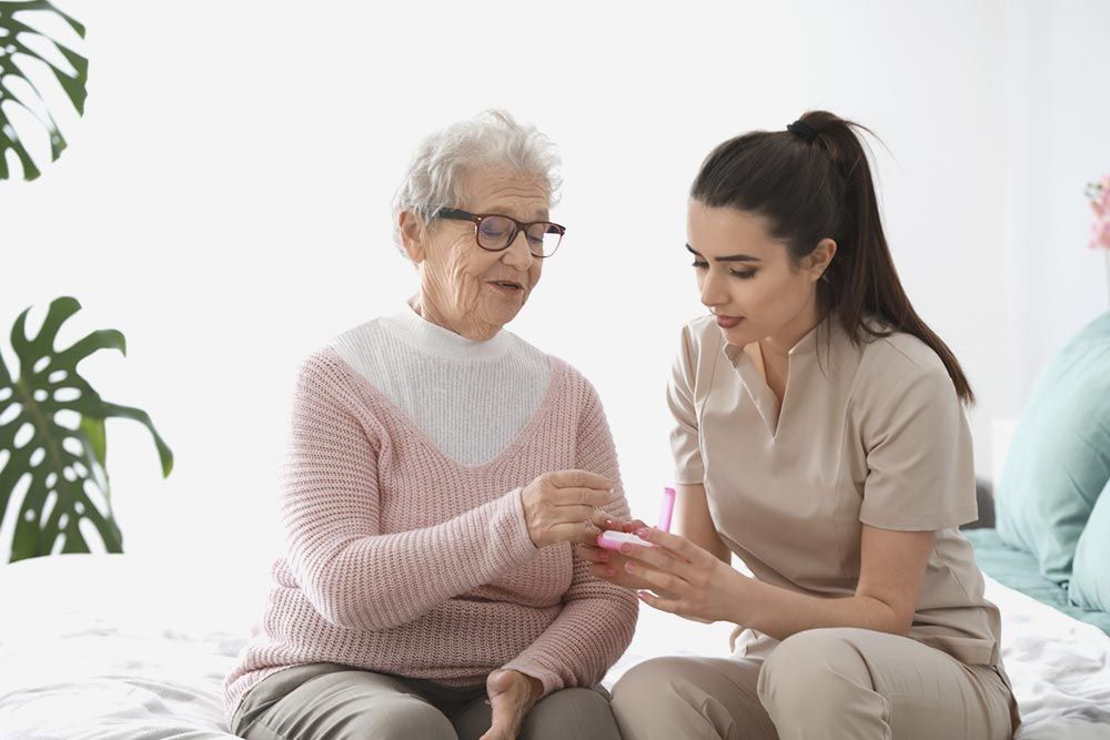 Una anciana está sentada en una cama con una enfermera.